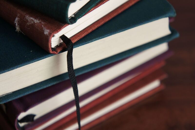 A stack of cloth-bound books with a ribbon bookmark hanging down